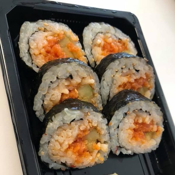 Six pieces of Blue Fin's spicy tuna sushi rolls with rice and seaweed in a black tray.