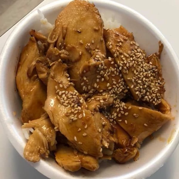 Close-up of Blue Fin's teriyaki chicken with sesame seeds over white rice in a bowl.